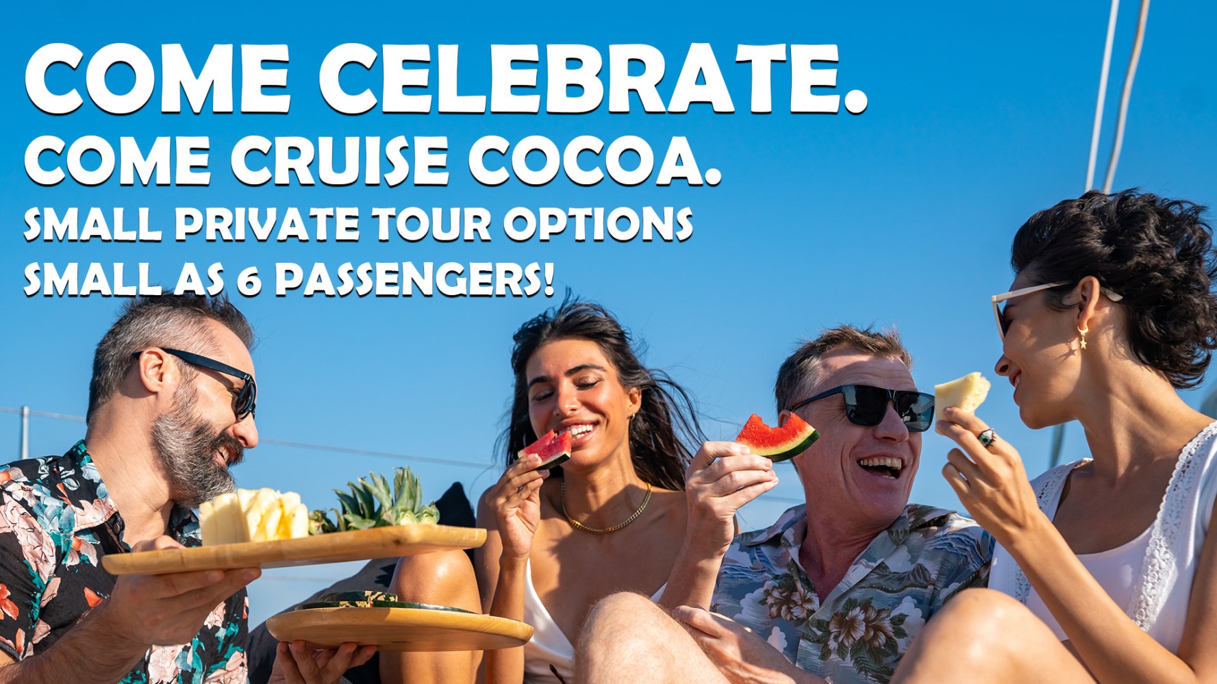 Four people on a boat laughing and enjoying fruit under clear blue sky.