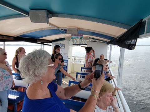 People on a boat taking photos and enjoying a scenic water view.
