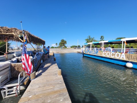 Two boats at a dock with 'Cruise Cocoa' on side, sunny day with palm trees.