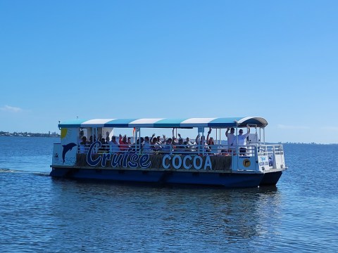 Tour boat 'Cruise Cocoa' with people onboard on a sunny day.