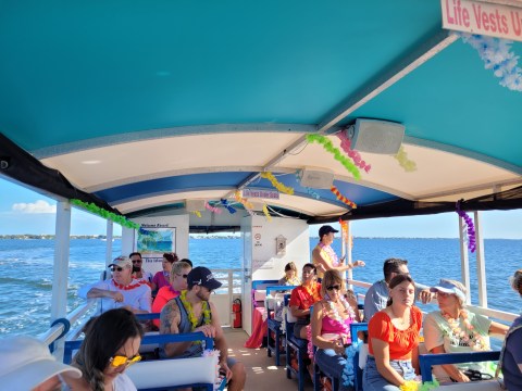 People on a boat wearing leis under a canopy, with a view of the ocean.