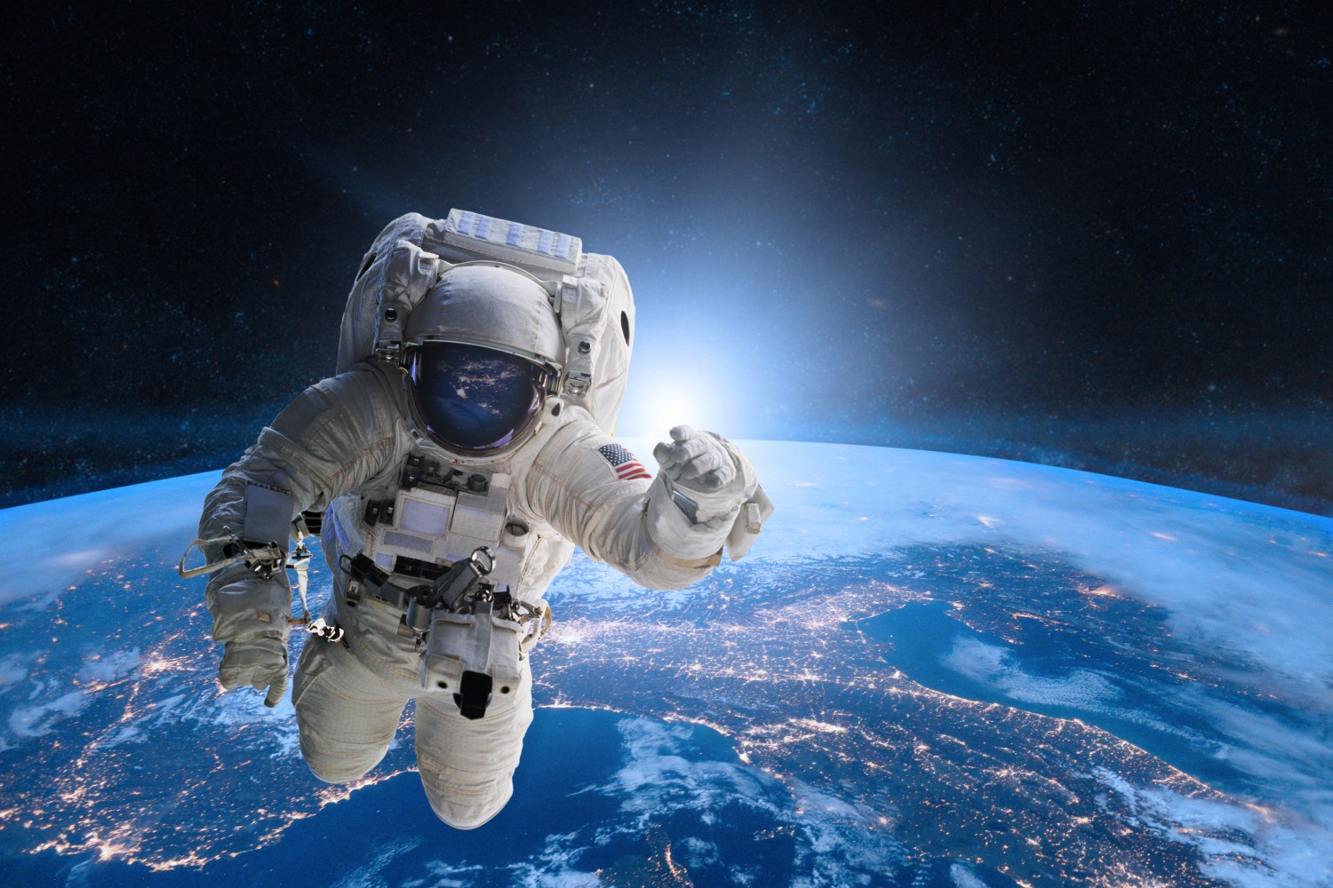 Astronaut floating in space above Earth with city lights visible.
