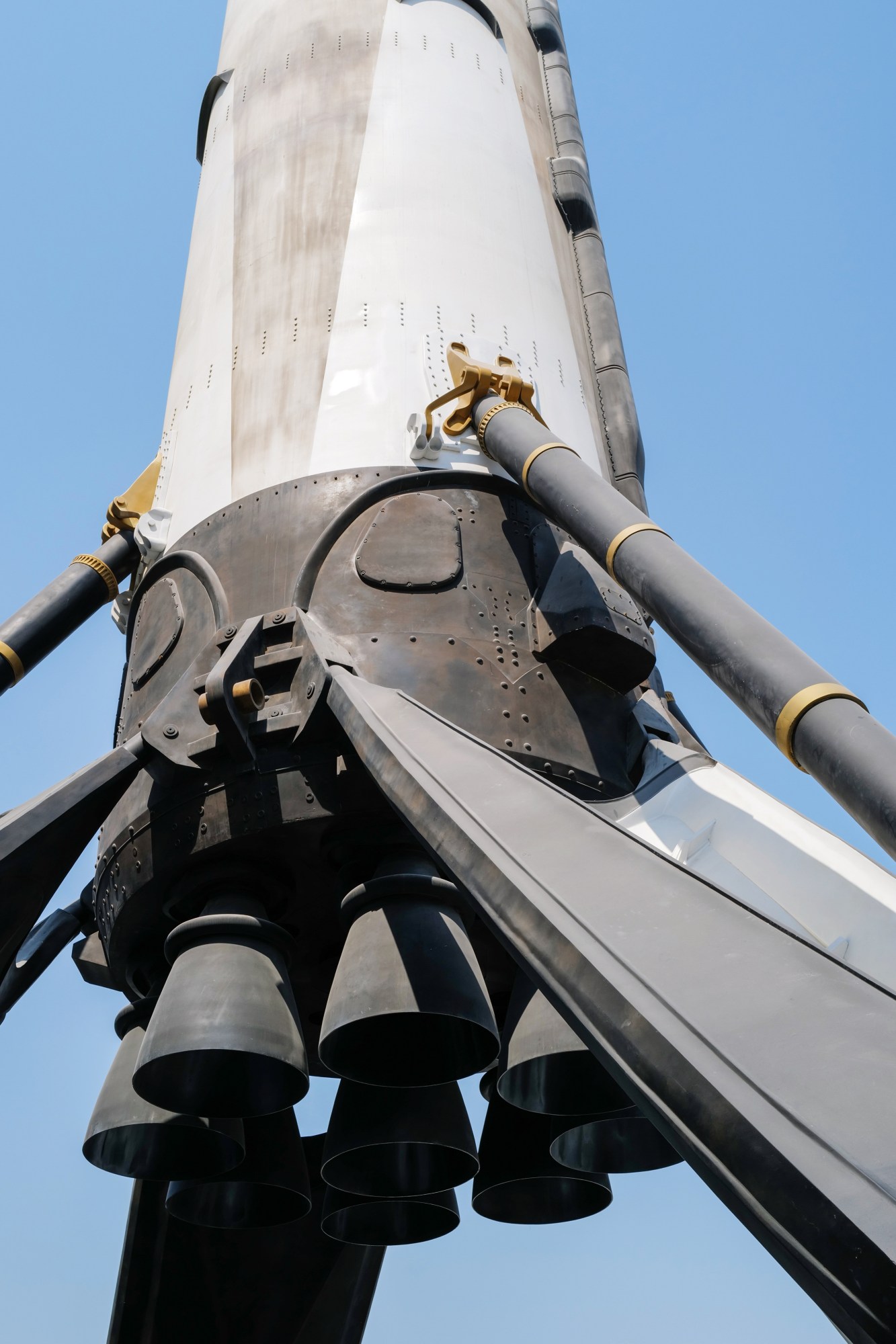 Close-up of a rocket's engines and exhaust nozzles against a clear blue sky.