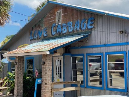Blue and gray building with a sign reading 'Love Cabbage' and a picnic table outside.