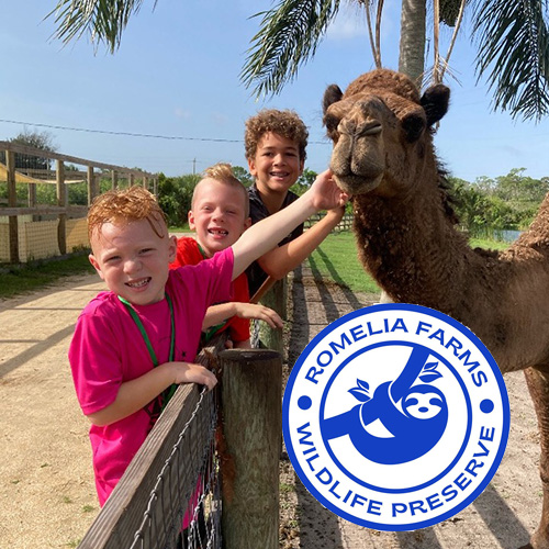 Three kids pet a camel at a wildlife preserve with a logo in the corner.