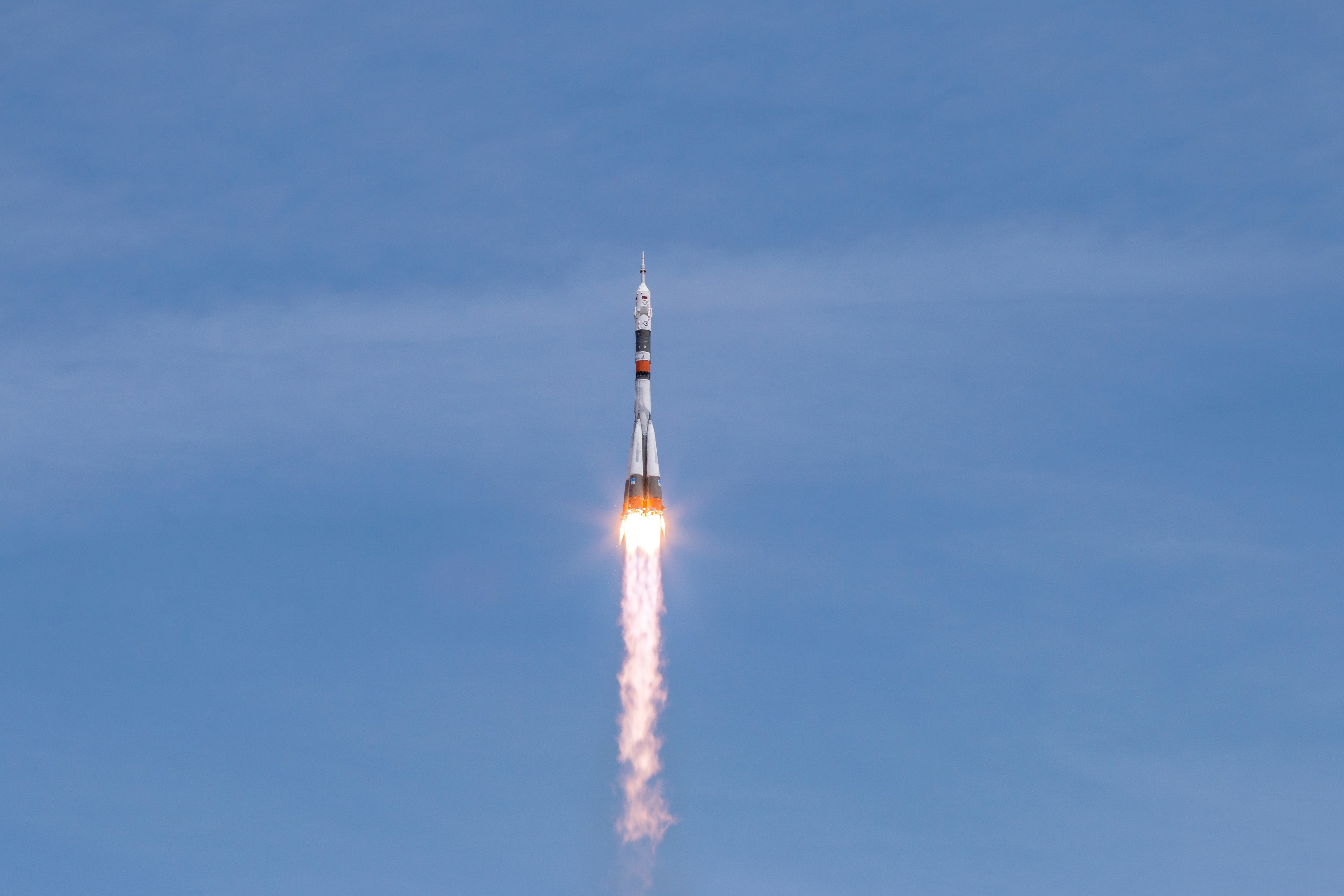 Rocket launching into a clear blue sky with visible flames.