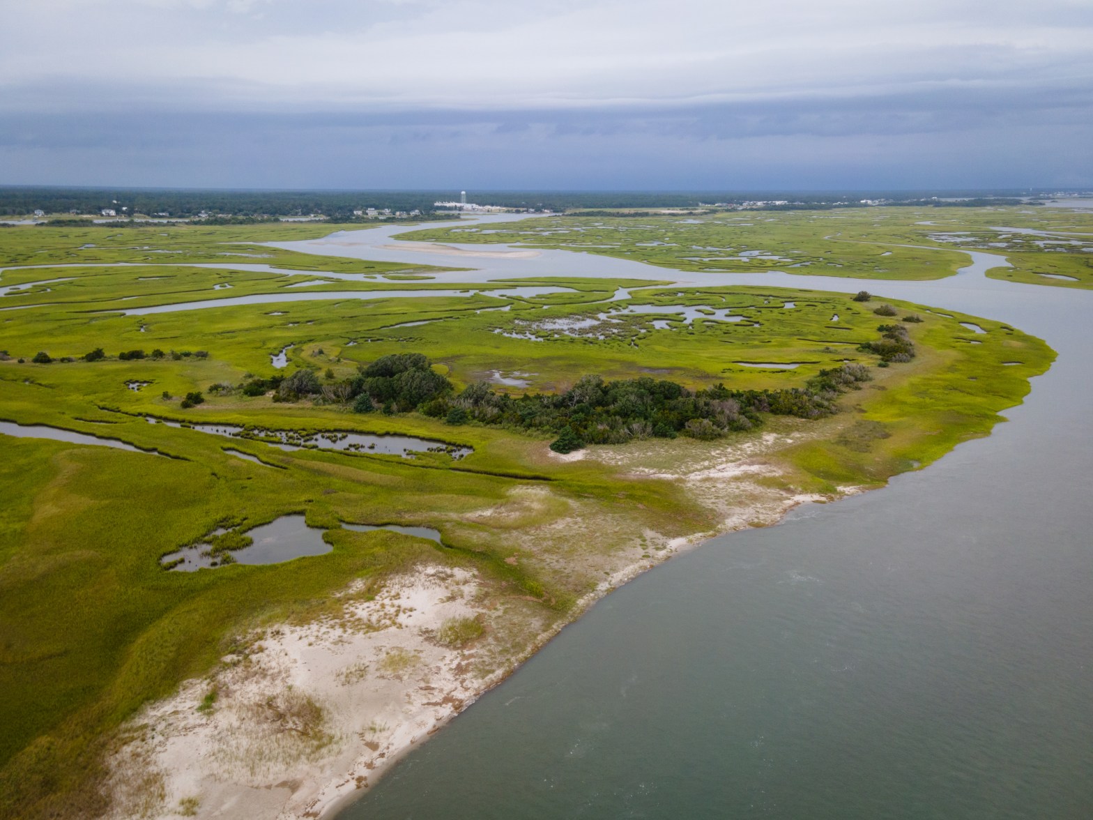Aerial view of a coastal marshland with winding water channels and grassy islands.
