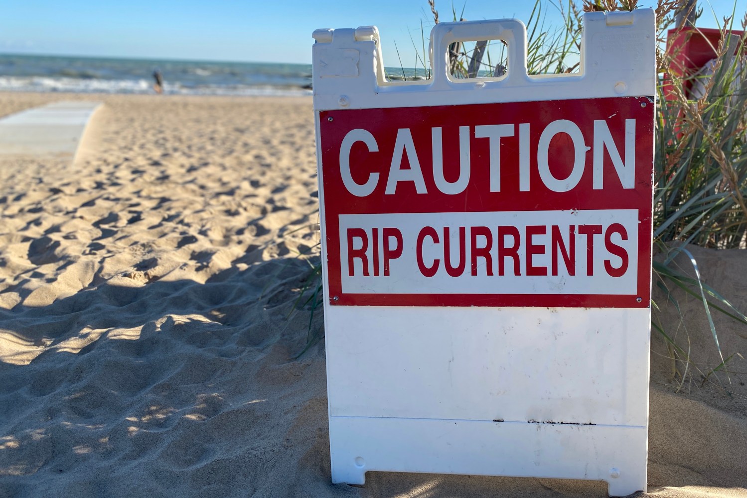 A beach sign warns: 'Caution Rip Currents.'