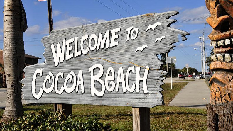 Wooden sign reading 'Welcome to Cocoa Beach' with seagull illustrations.