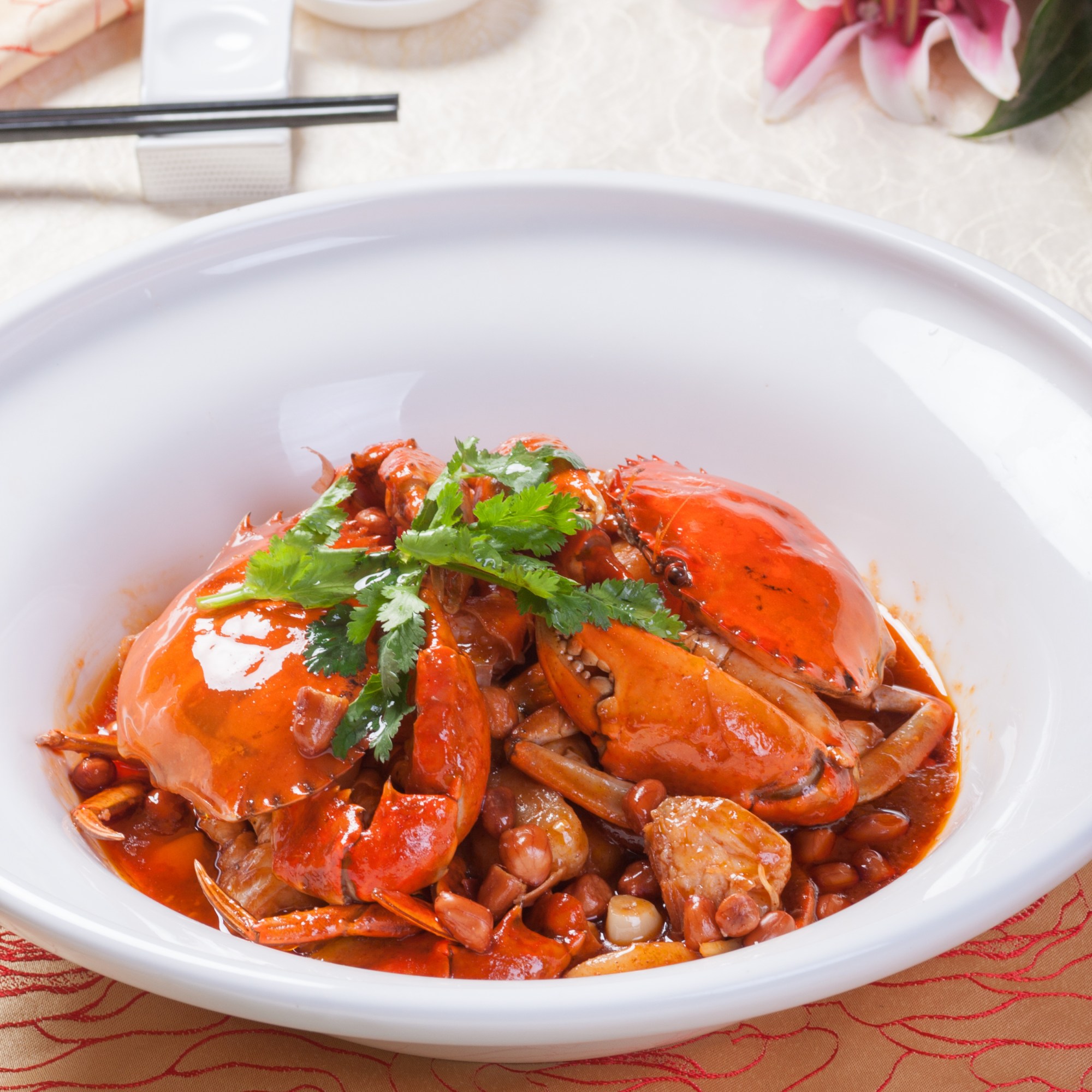 A dish of chili crab garnished with cilantro in a white bowl.