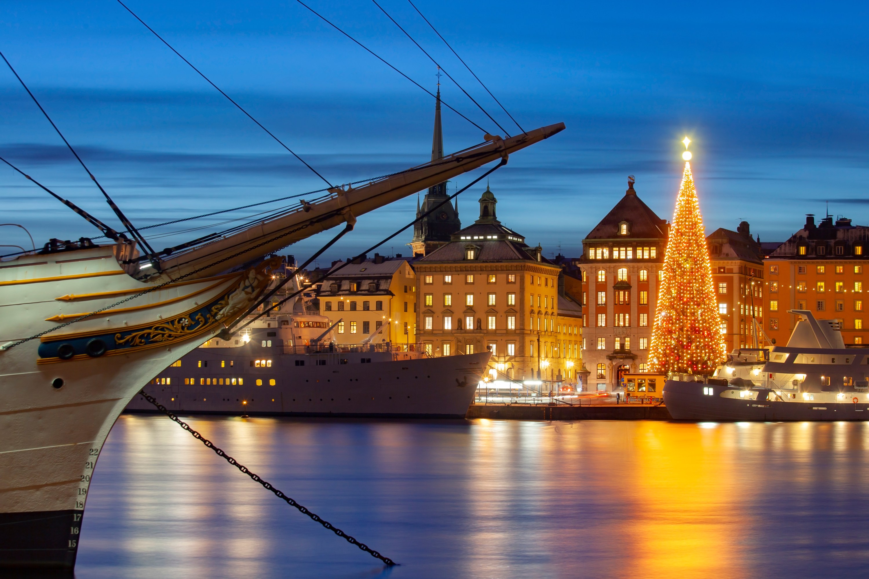 Illuminated cityscape with decorated Christmas tree and ship at night.