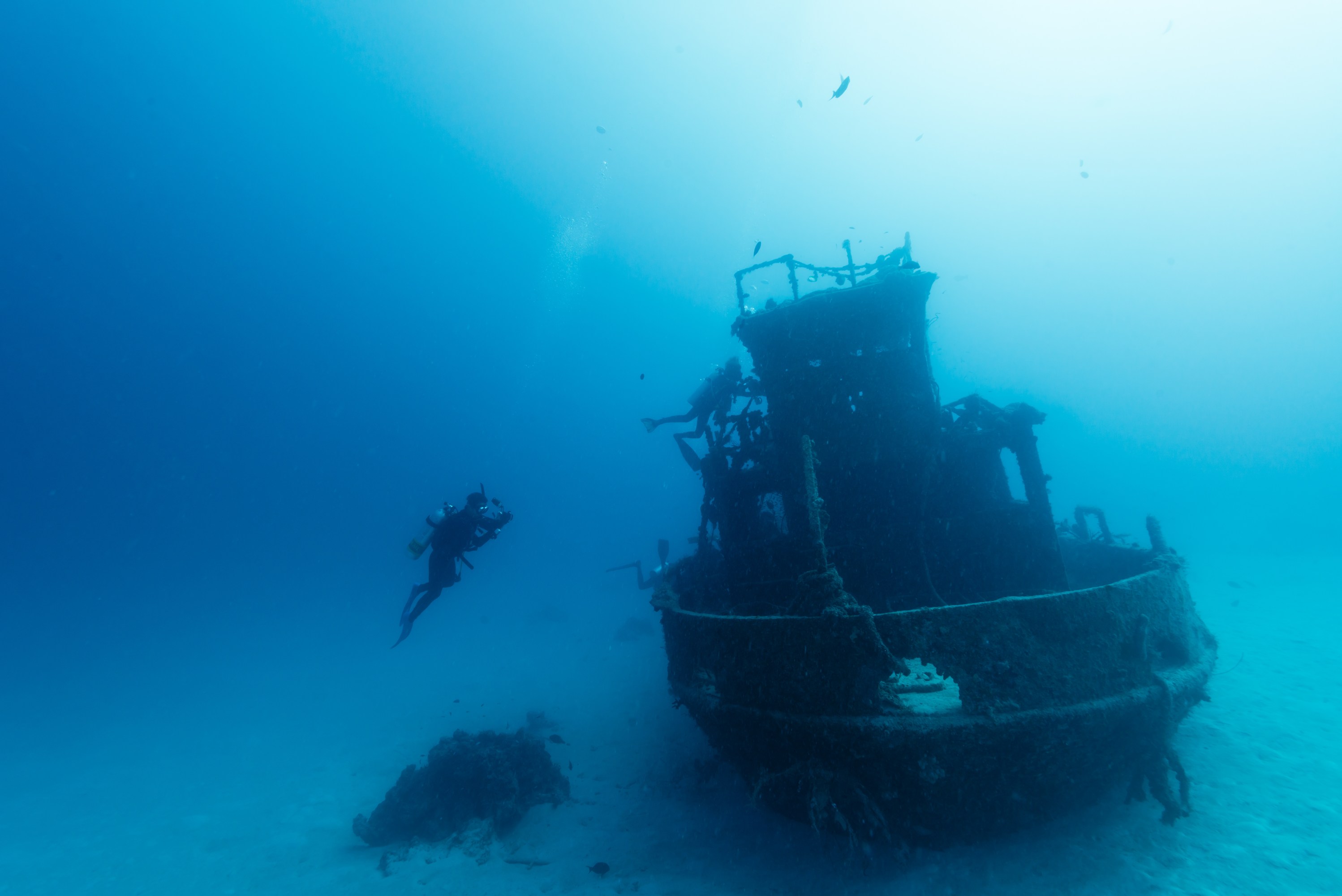 Diver exploring a sunken shipwreck on the ocean floor.