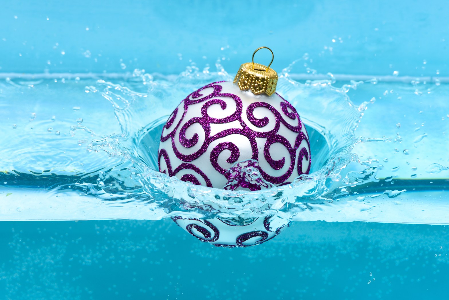 A decorative purple and white ornament splashing into clear blue water.