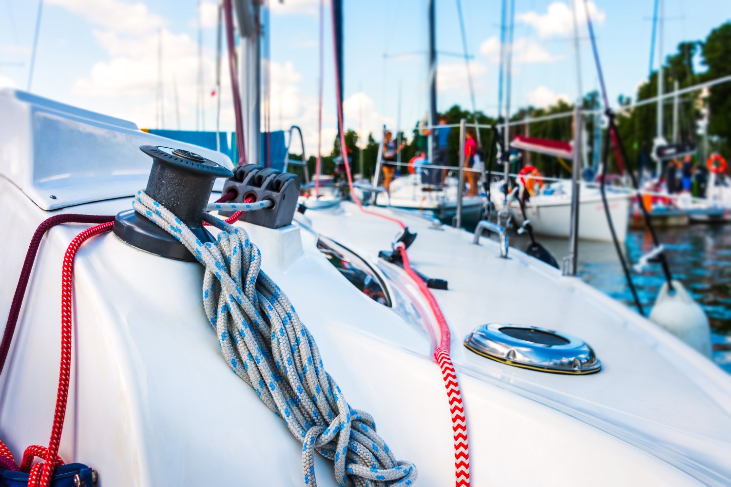 Close-up of a sailboat deck with coiled ropes, marina in background.