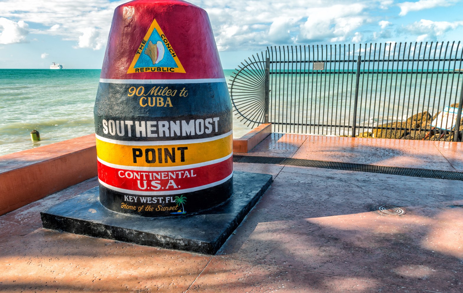 Buoy-shaped Southernmost Point marker in Key West, Florida, near ocean.