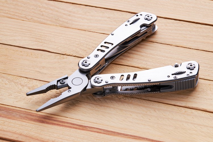 Open multi-tool with pliers on a wooden surface.