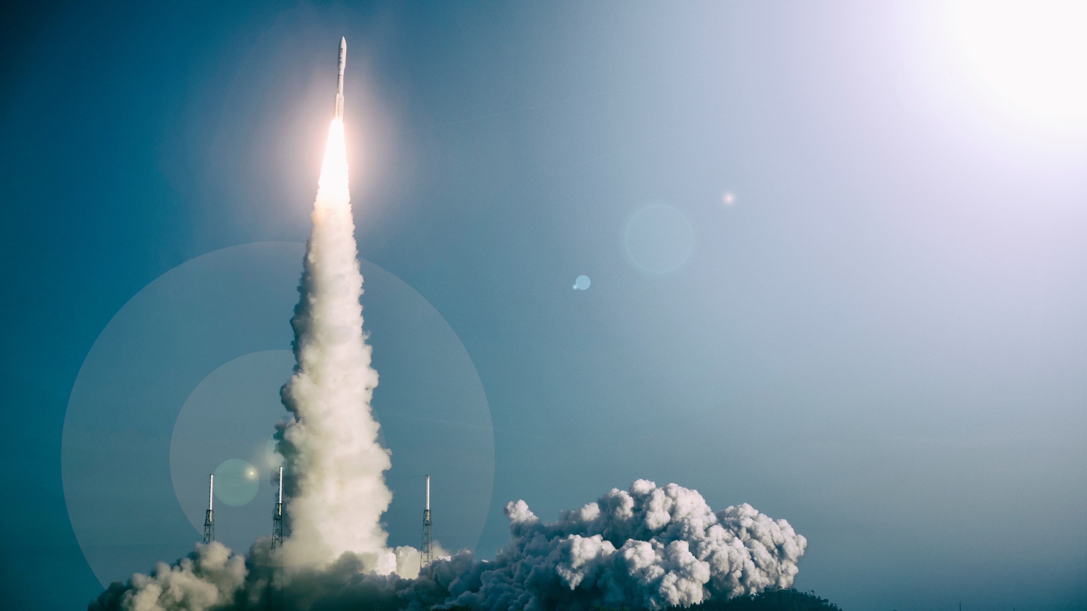 A rocket launching with a trail of smoke against a clear sky.