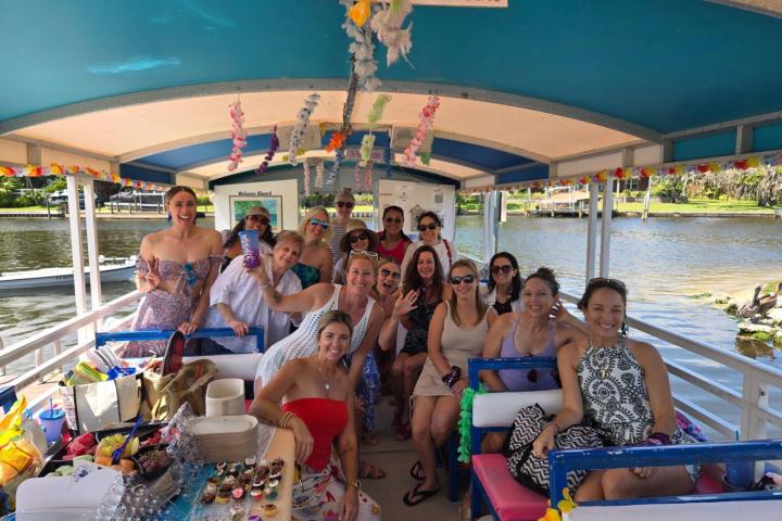 Group of people smiling on a decorated boat with snacks and drinks.